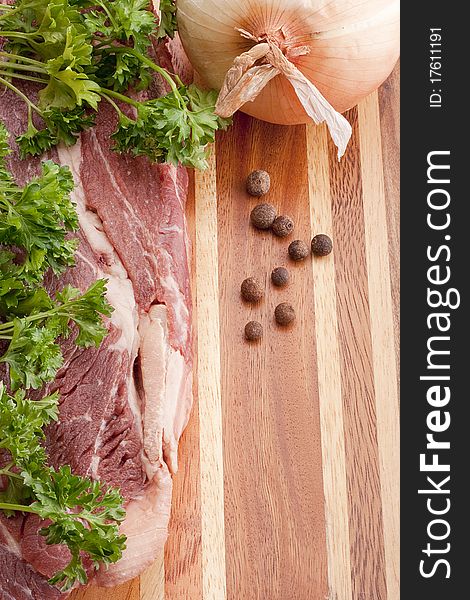 A piece of raw meat on a multilayer wooden kitchen cutting board.