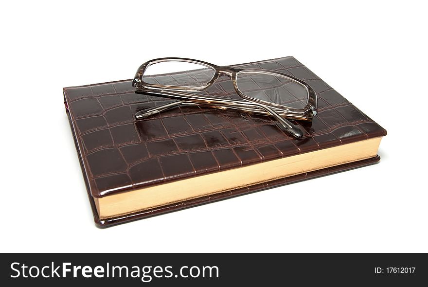 Leather diary and glasses on a white background