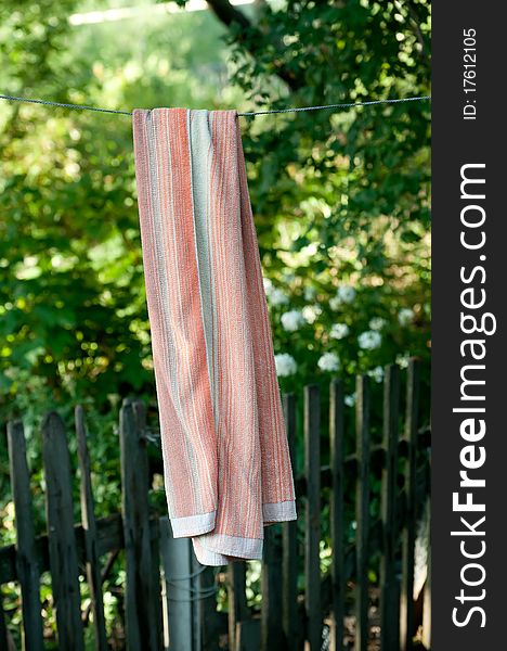 Clean towel hangs against greens. Rural scene. Clean towel hangs against greens. Rural scene.