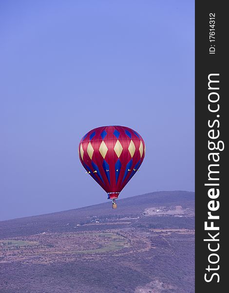 Verticle image of a red hot balloon flying in the mountains of central mexico. Verticle image of a red hot balloon flying in the mountains of central mexico