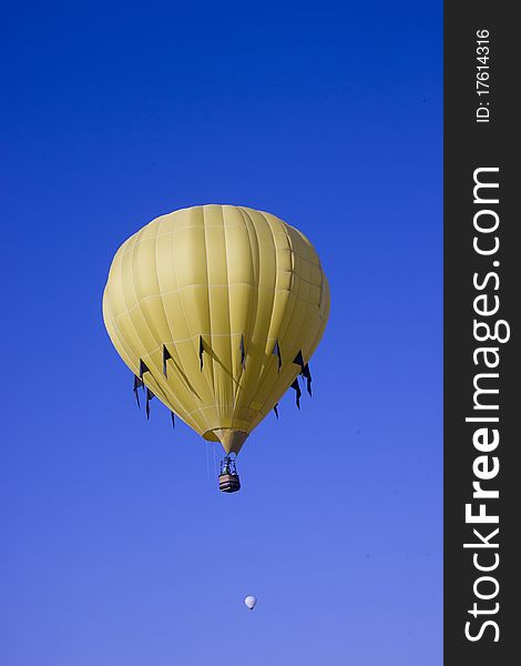 Verticle image of a yellow hot balloon flying in a clear blue sky. Verticle image of a yellow hot balloon flying in a clear blue sky