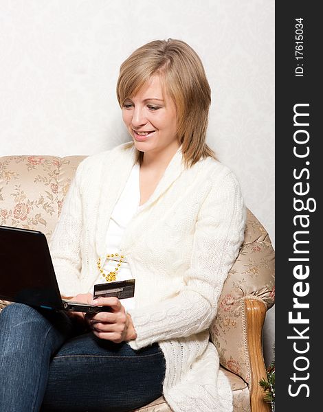 A young woman sits with a notebook on a soft sofa. A young woman sits with a notebook on a soft sofa