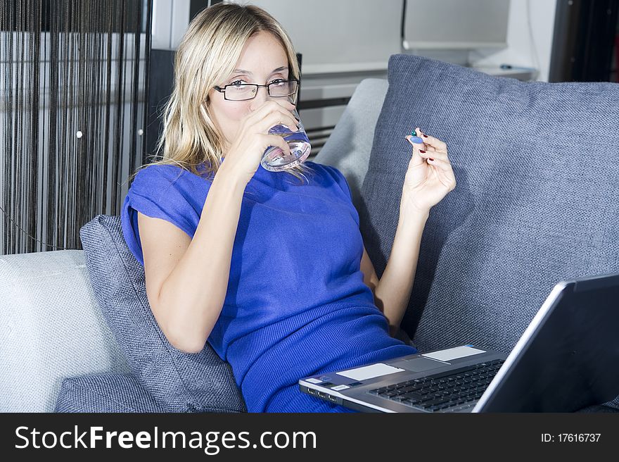 Blond woman taking a pill with a glass of water