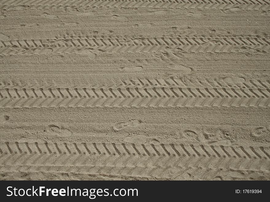 Footprints and tyre tracks in sand