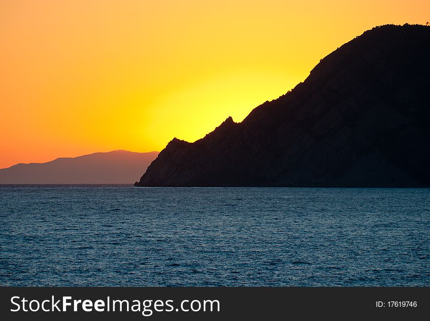 Beatifyl orange sunset over the blue sea behind the mountain. Beatifyl orange sunset over the blue sea behind the mountain