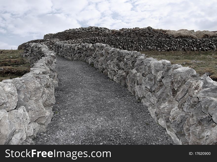 Rocky walls and path against a cloudy scenic background in ireland. Rocky walls and path against a cloudy scenic background in ireland