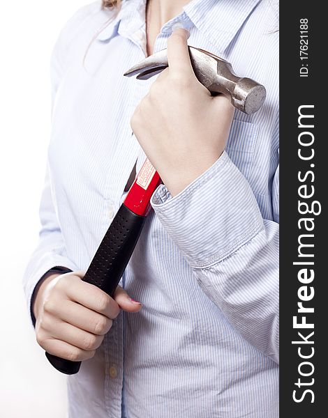 A woman in business attire holding a hammer at her chest. A high key portrait on a white background. Woman is wearing a blue button up shirt. A woman in business attire holding a hammer at her chest. A high key portrait on a white background. Woman is wearing a blue button up shirt.