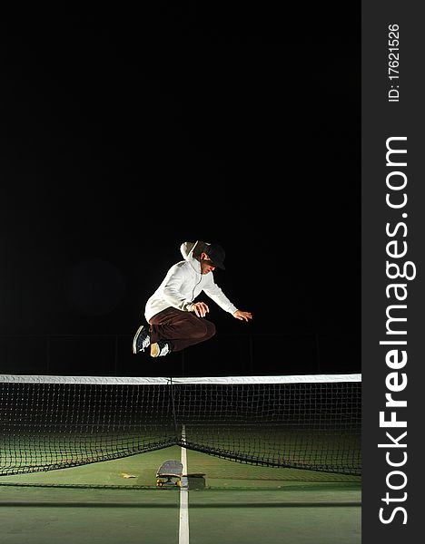 A young skaterboarder doing a Hippie Jump over a tennis net. A young skaterboarder doing a Hippie Jump over a tennis net
