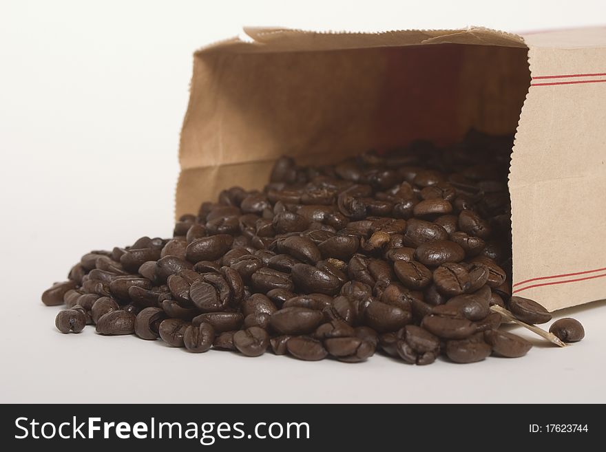 Multiple, brown coffee beans in a brown paper bag