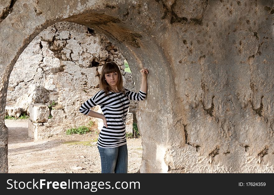 Young girl in jeans in an arch in the ruins