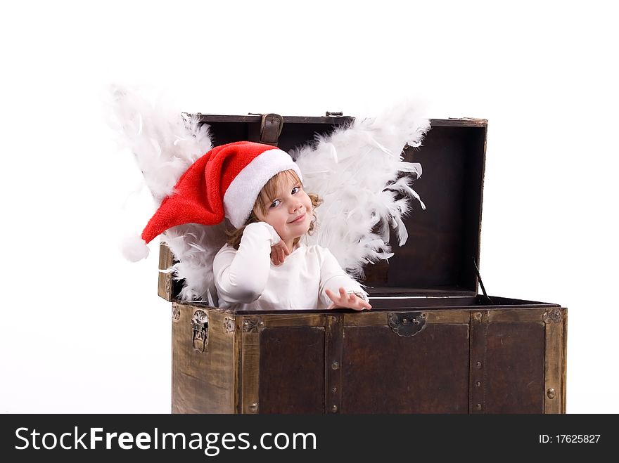 Girl with angel wings in cap of Santa Claus sitting in a box. Girl with angel wings in cap of Santa Claus sitting in a box.