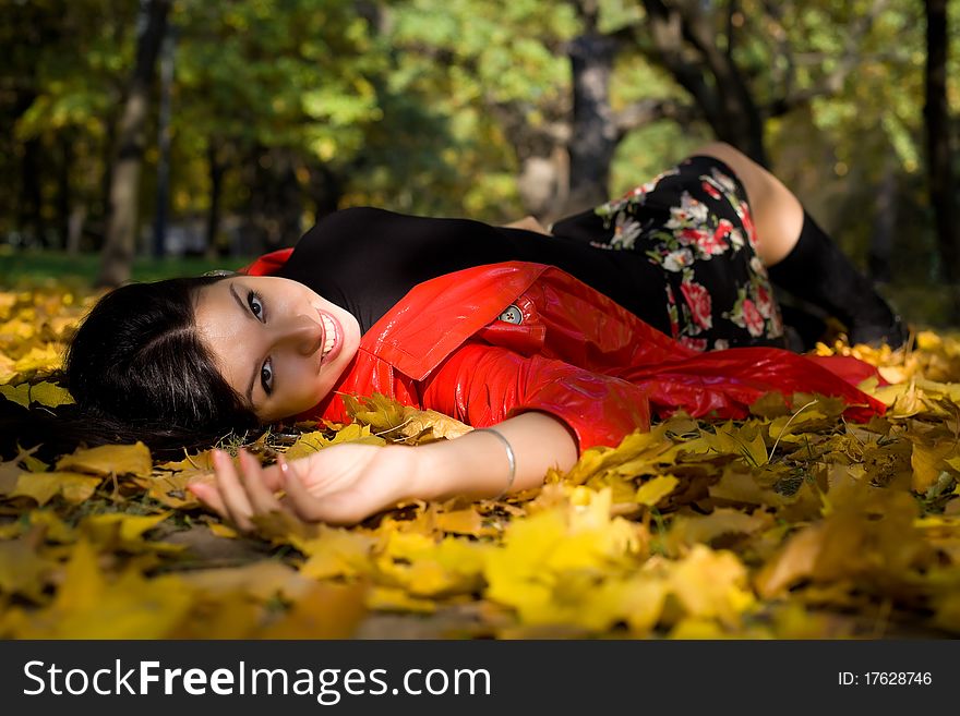 Young woman in autumn park lay on ground