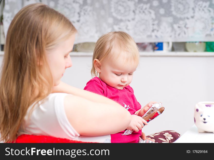 Young mother eat chocolate with adorable daughter in kitchen