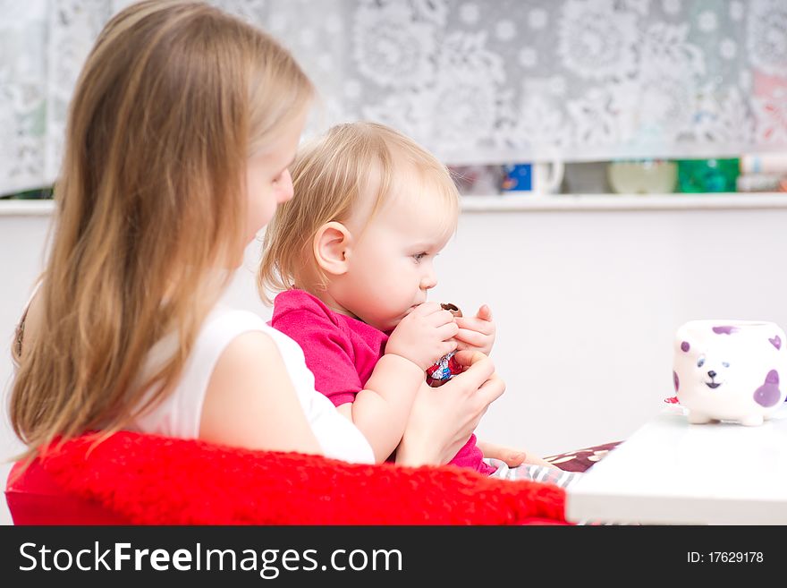 Young mother eat chocolate with adorable daughter in kitchen