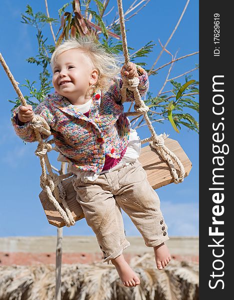 Little cute happy girl swinging outdoors in sunlight. Little cute happy girl swinging outdoors in sunlight