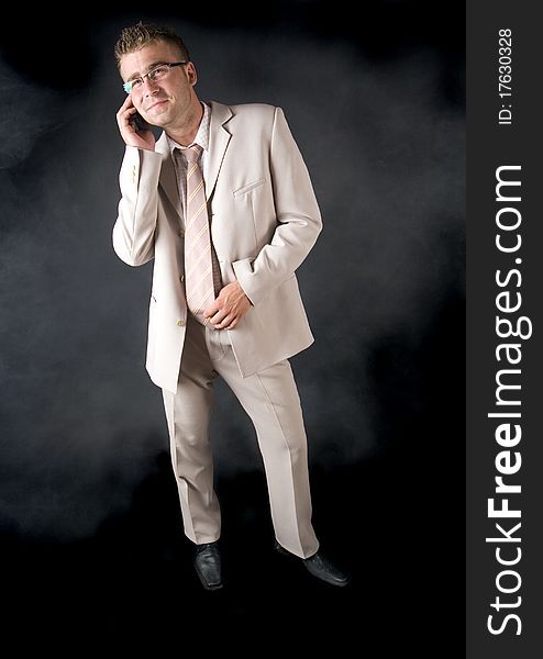 Elegant man standing on a black background. Businessman talking on the phone