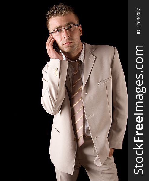 Elegant man standing on a black background. Businessman talking on the phone