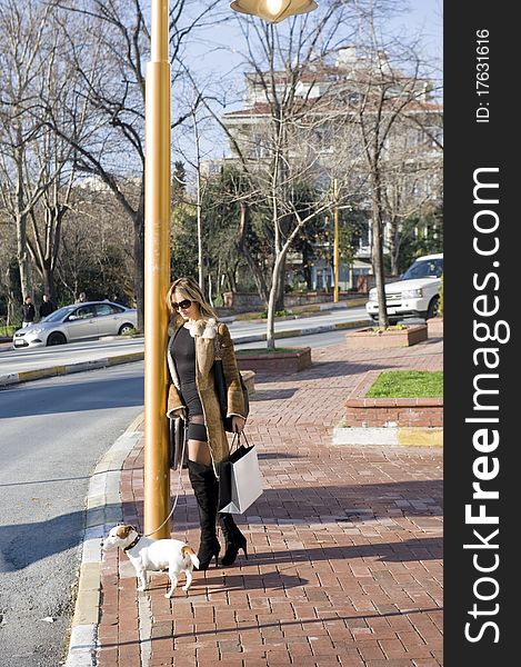Blond woman walking down the fashion district of a modern city with a jack russel. Blond woman walking down the fashion district of a modern city with a jack russel