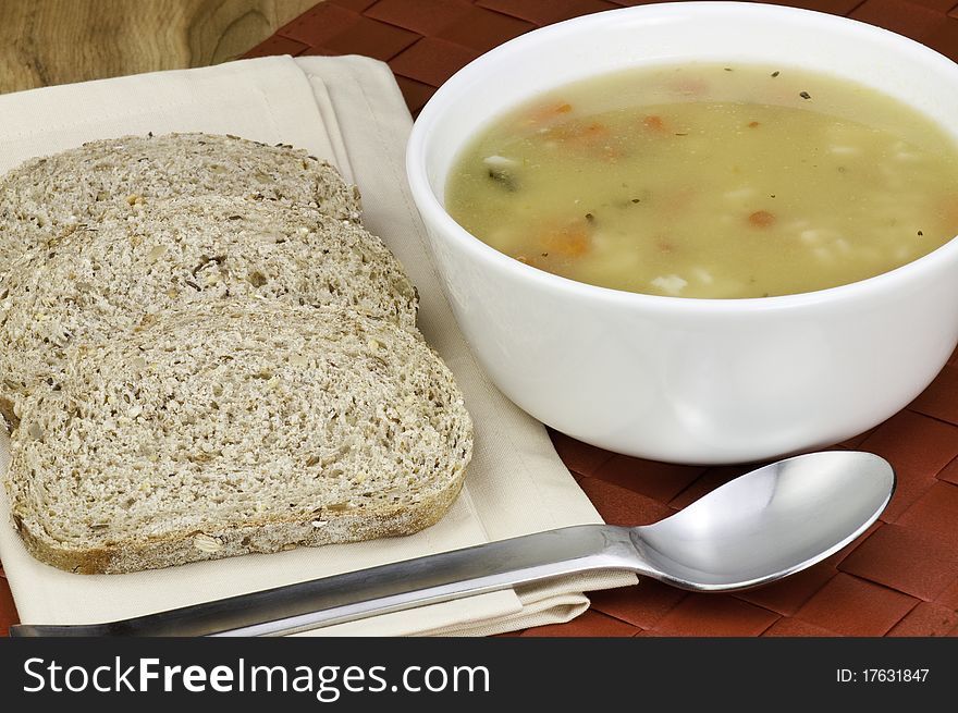 A bowl of healthy chicken soup and whole grain bread. A bowl of healthy chicken soup and whole grain bread