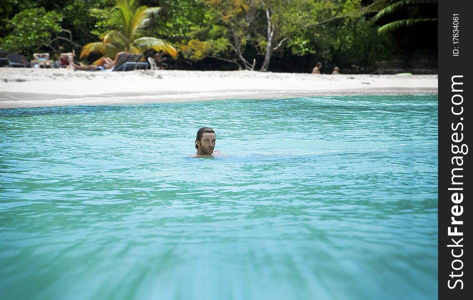 Scenic photo of a young man on vacation in beautiful chrystal clear tropical waters with shallow depth of field