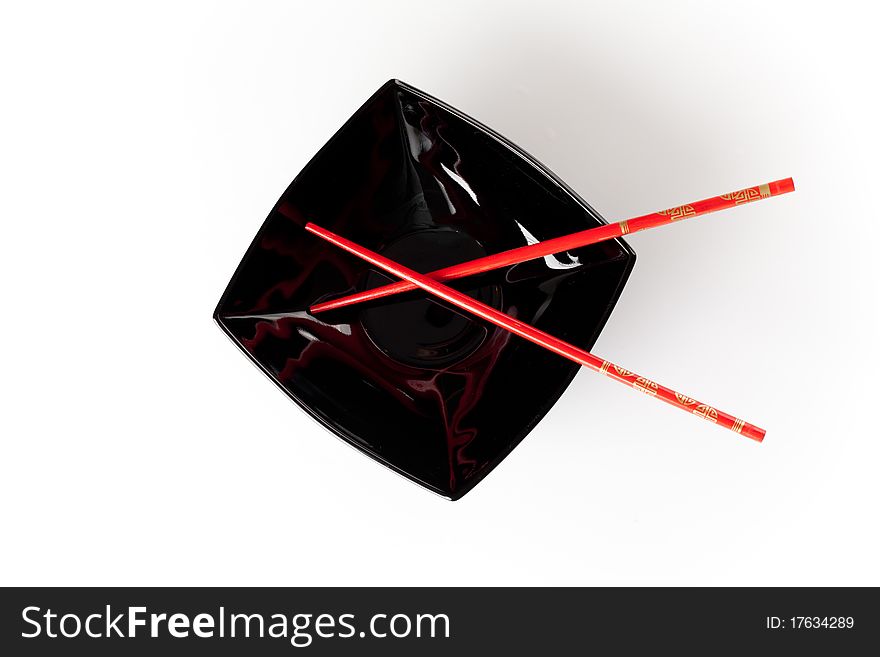 Black plate with red chopsticks isolated