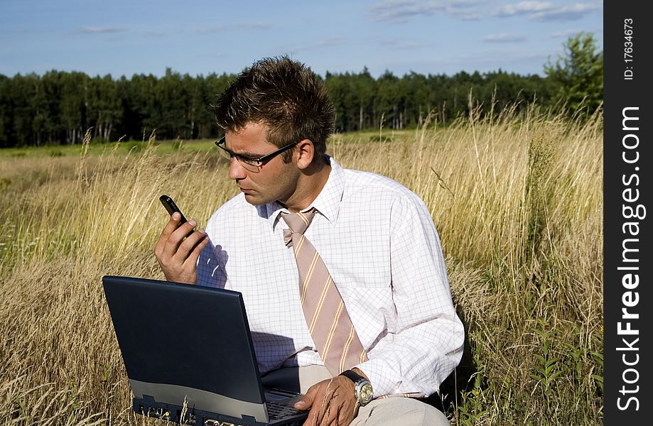Elegant businessman working on his laptop in nature.