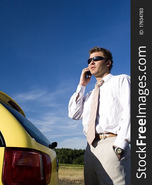 A businessman dressed in a smart suit standing on grass and talking on mobile phone. A businessman dressed in a smart suit standing on grass and talking on mobile phone.