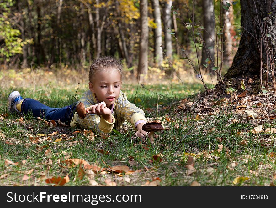 A smiling girl is laying on a grass in the forest. A smiling girl is laying on a grass in the forest