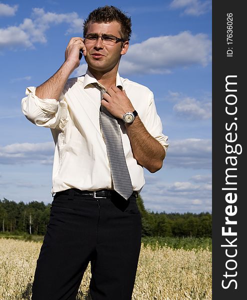 A businessman dressed in a smart suit standing on grass and talking on mobile phone. A businessman dressed in a smart suit standing on grass and talking on mobile phone.