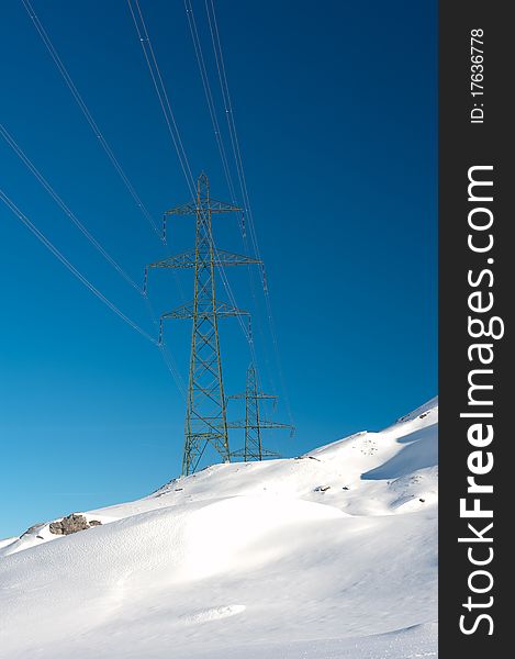 Power poles in a snowy landscape with bright blue sky