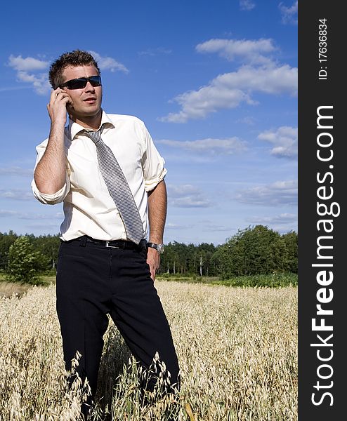 A businessman dressed in a smart suit standing on grass and talking on mobile phone. A businessman dressed in a smart suit standing on grass and talking on mobile phone.