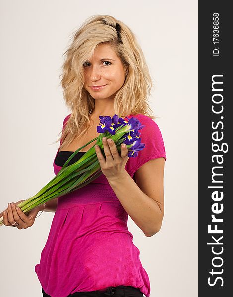 Beautiful girl with blonde hair holding a bouquet of irises. She is in studio isolated on a white background. Beautiful girl with blonde hair holding a bouquet of irises. She is in studio isolated on a white background