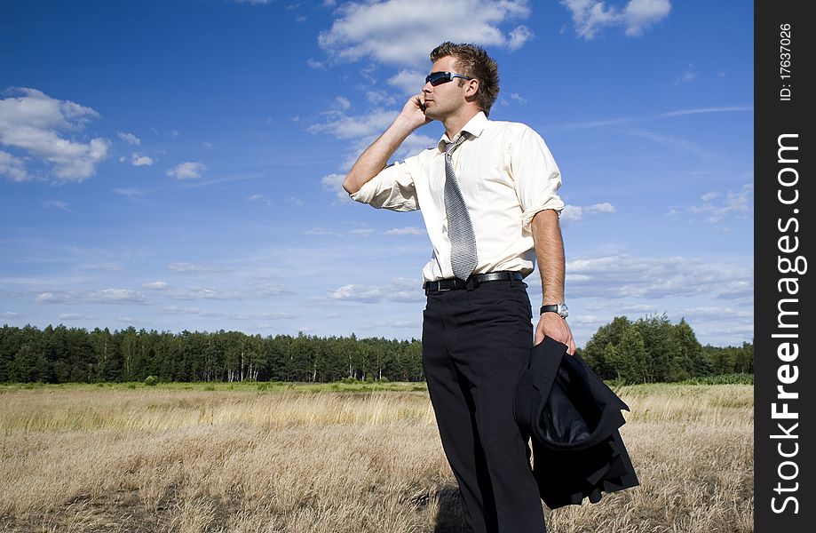 A businessman dressed in a smart suit standing on grass and talking on mobile phone. A businessman dressed in a smart suit standing on grass and talking on mobile phone.