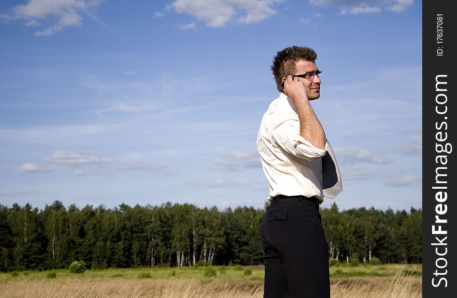 A businessman dressed in a smart suit standing on grass and talking on mobile phone. A businessman dressed in a smart suit standing on grass and talking on mobile phone.