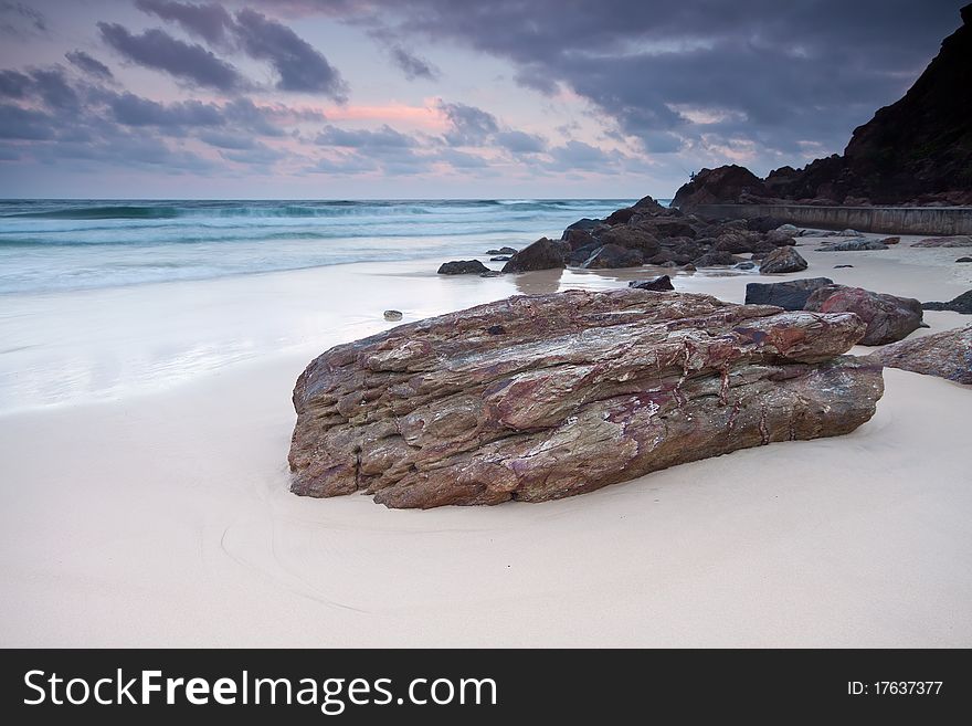 The beach at twilight with large rock in foreground