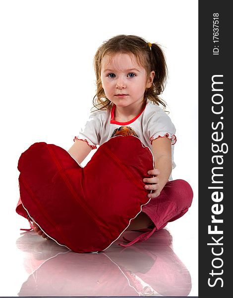 Beautiful girl sitting with heart shaped red pillow in red angel wings isolated on white