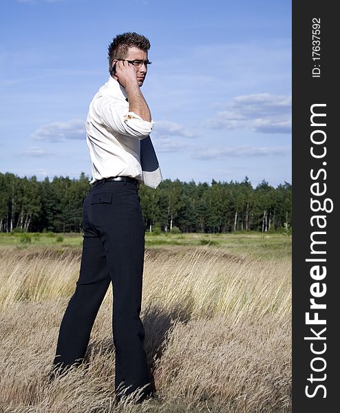 A businessman dressed in a smart suit standing on grass and talking on mobile phone. A businessman dressed in a smart suit standing on grass and talking on mobile phone.