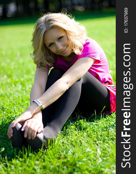 Young beautyful girl sitting on grass on a sunny day in a park. Young beautyful girl sitting on grass on a sunny day in a park