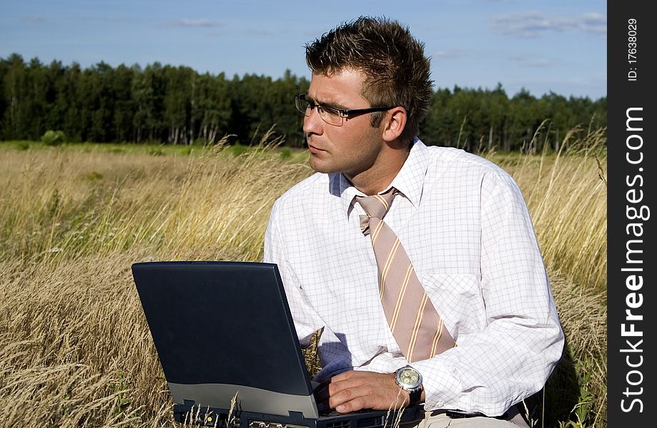 Elegant businessman working on his laptop in nature.