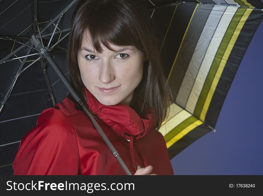 Portrait of a young woman holding an umbrella over blue background