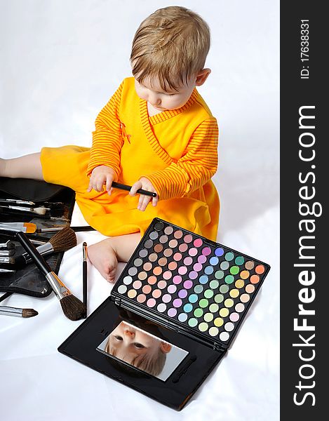 The child plays cosmetics and brushes. The child plays cosmetics and brushes