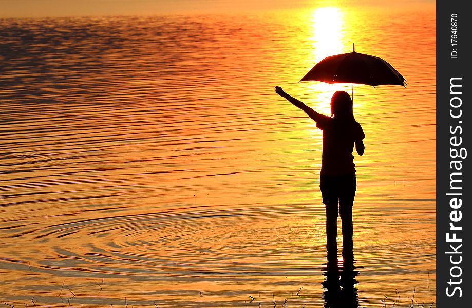 Silhouette of young woman wading in sea at sunset. Silhouette of young woman wading in sea at sunset