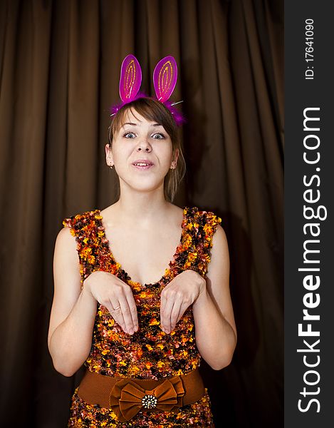 Woman with pink rabbit ears on brown background. Woman with pink rabbit ears on brown background