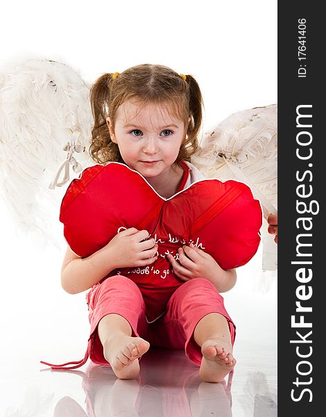 Beautiful girl sitting with heart shaped red pillow isolated on white