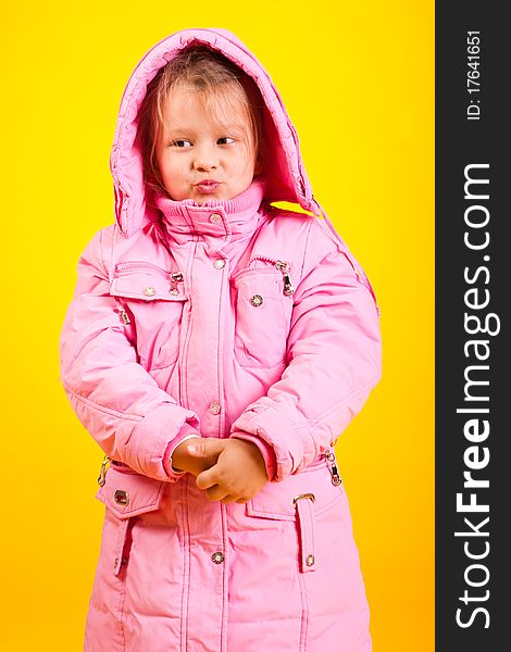 Little girl in an overcoat on a yellow background