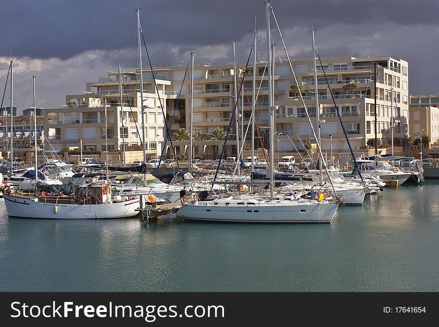 An image of Yachts anchored at the marina with stormy weather and cloudy sky