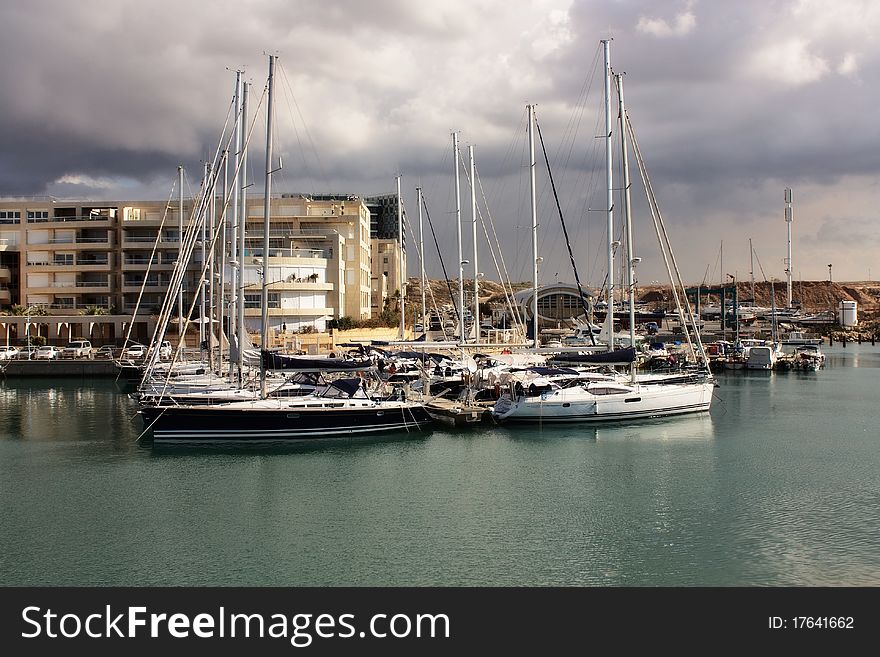 An image of Yachts anchored at the marina with stormy weather and cloudy sky