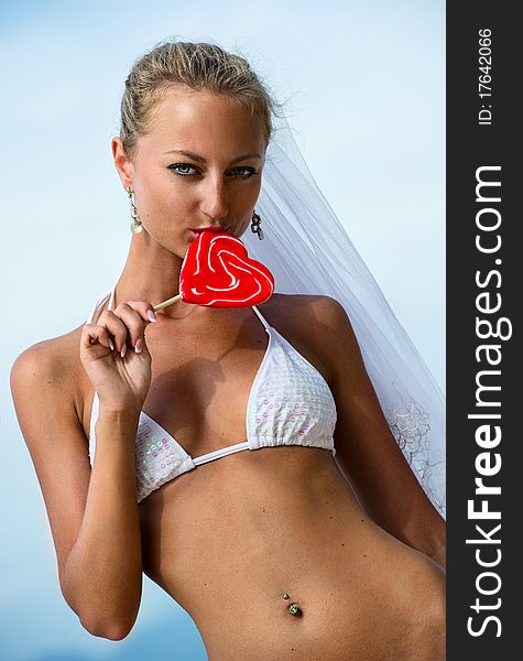 Beautiful bride holding a lollipop on the beach. Beautiful bride holding a lollipop on the beach