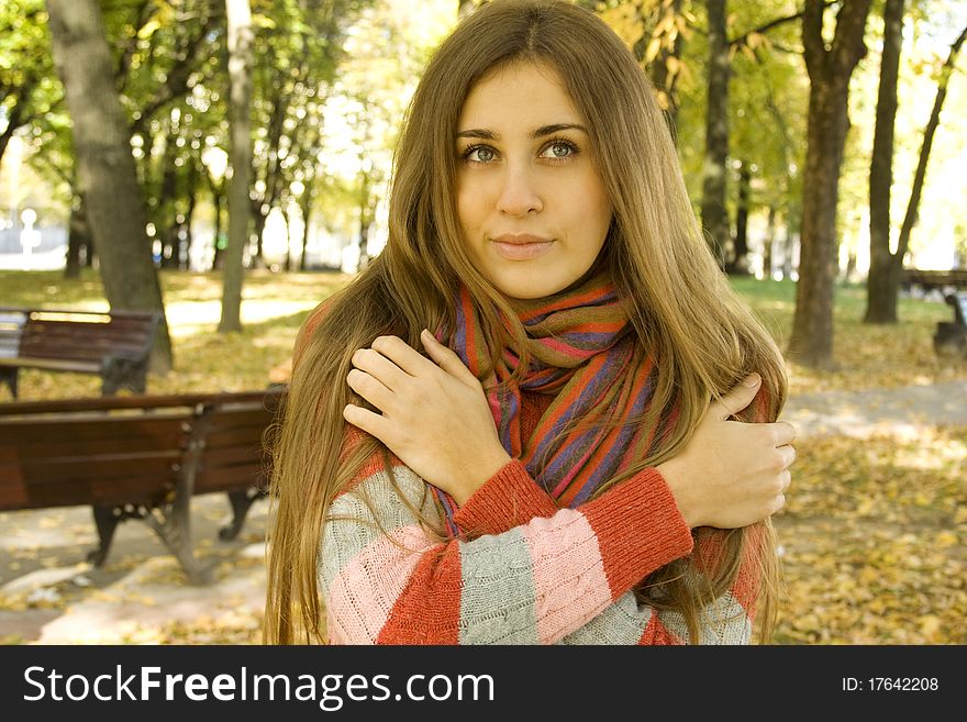 Autumn portrait of a beautiful young woman against yellow leaves. The girl was wrapped in a scarf