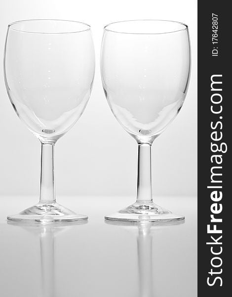 Two empty wine glasses with a white background and reflection. Two empty wine glasses with a white background and reflection